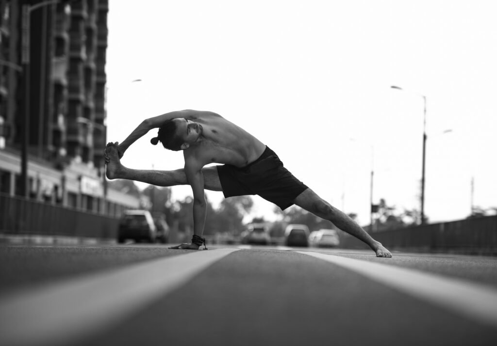 artistic photo of a man doing calisthenics on a road in black and white
